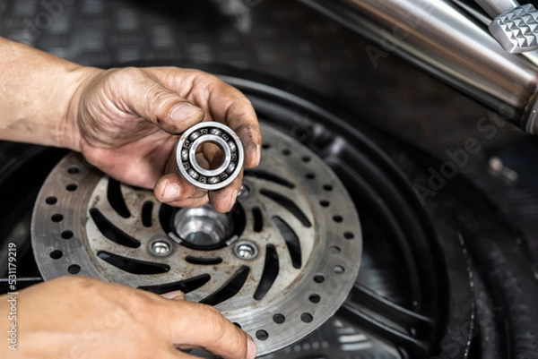 Obraz Mechanic check and replace Motorcycle wheel bearings , working in garage . repair and  maintenance motorcycle concept .selective focus