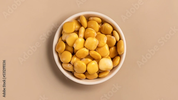 Fototapeta salted lupins in white bowl standing on beige background, Flay lay