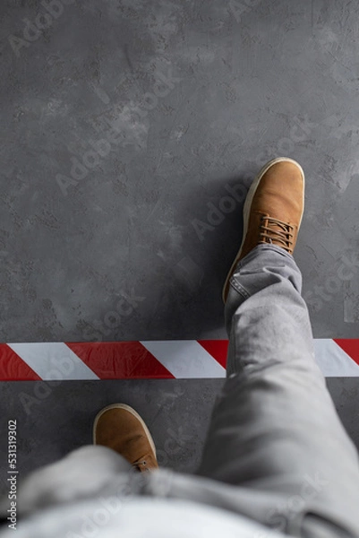 Fototapeta Man stepping over signal warning tape  at cement floor background. Moving forward  concept idea