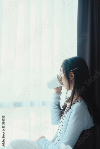 Obraz woman doing sitting at window after wake up with coffee mug