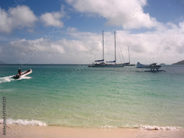 Fototapeta Several boats and a seaplane on the beach in the Whitsunday Islands in Australia