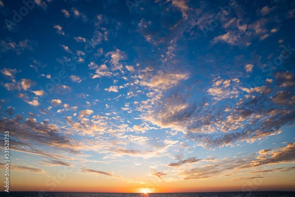 Obraz Sunset sky with clouds over the sea. Clouds in the sky in sunset sunlight. Beautiful sunset sky with clouds. Evening sunset.