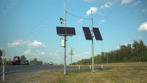 Fototapeta Solar panels on two poles in the steppe near the road. Camera for fixing traffic violations.