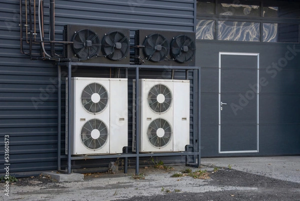 Fototapeta Air conditioning chiller units mounted on a frame near a building wall