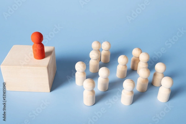 Obraz A red figure stands on a pedestal addressing a group of identical figures. The concept of leadership, recitation, meetings