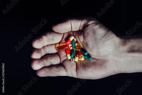 Obraz Mountain of pills in the hand of a doctor on an isolated black background