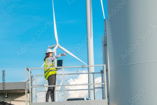 Fototapeta women engineer working and holding the report at wind turbine farm Power Generator Station on mountain,Thailand people