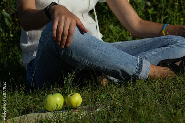 Obraz white apples lie on a book, woman sitting back
