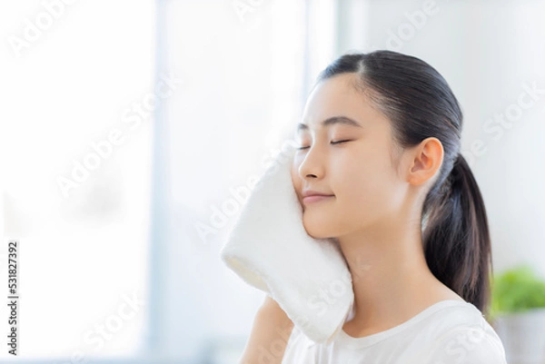 Fototapeta タオルで顔を拭く若い女性