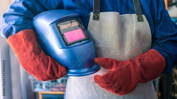 Fototapeta A man welder with safety helmet working with arc welding machine in the workshop