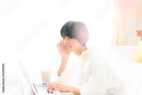 Fototapeta コピースペースが使いやすい綺麗な逆光の中仕事をする女性　ピンクの前ボケあり　カメラ目線