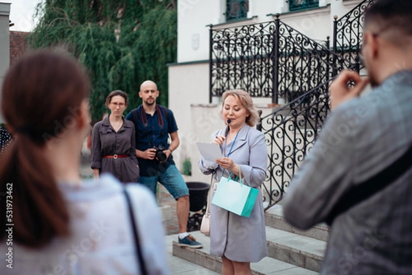 Obraz guide and a group of tourists standing on the steps of the hotel.