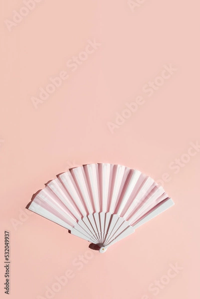 Fototapeta White fan on beige background with hard shadows. Minimal concept of menopause and female hot flashes. Vertical banner, copy space