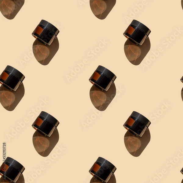 Obraz Seamless pattern of mock-ups of jars for cosmetic products made of amber glass on beige background. Unmarked packaging with face cream, hands with hard shadows close-up