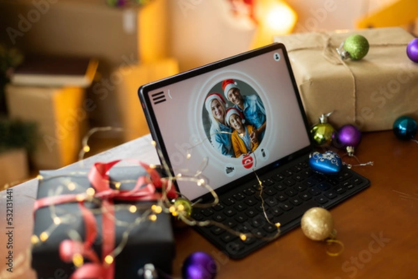 Fototapeta Big family singing christmas song at tablet camera during online video call. Smiling parents and children. Joyful family congratulating relatives with happy new year online