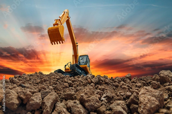 Fototapeta Crawler Excavator is digging with lift up in the construction site  on sunset white background.