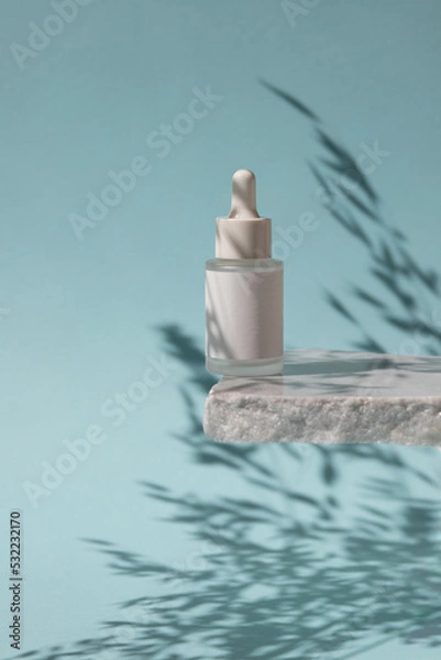 Fototapeta White Matte glass dropper bottle with shadows on marble platform  on blue background. Product concept