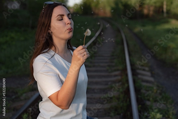 Obraz woman blowing on a dandelion. portrait of a woman.