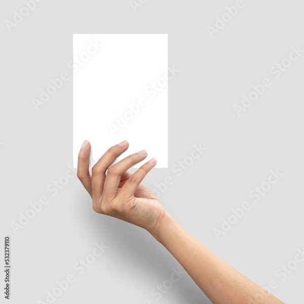 Fototapeta Close up of  woman hand holding blank paper sheet A5 size on grey background.