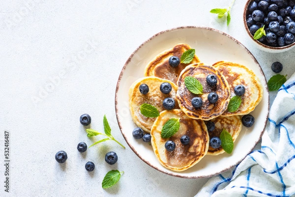 Obraz Pancakes with fresh blueberries and honey at white table. Healthy breakfast or dessert. Top view with copy space.