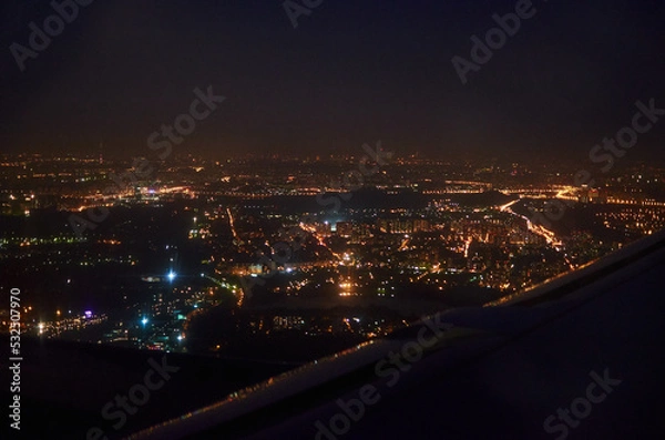 Fototapeta view from the window of the plane on the night city. bird's eye view of city lights at night
