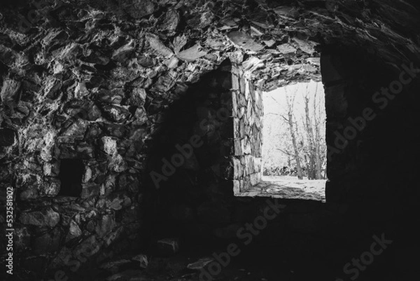 Obraz Dungeon and tunnel in Sveaborg fortress. Helsinki, Finland. Atmospheric sightseeing. Rays of light shining into empty old cellar. Trees outside. Texture and structure of aged stone walls. Monochrome