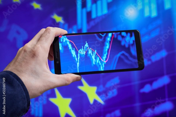 Obraz Trader analyzes stock market data in smartphone on the background of stock charts