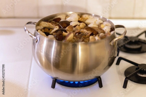 Fototapeta Mushrooms are cooked in boiling water in a saucepan on a gas stove.