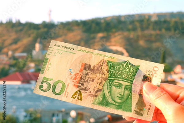 Fototapeta 50 Georgian Lari Banknotes in Obverse Side in Hand with Blurry Tbilisi City View in Backdrop