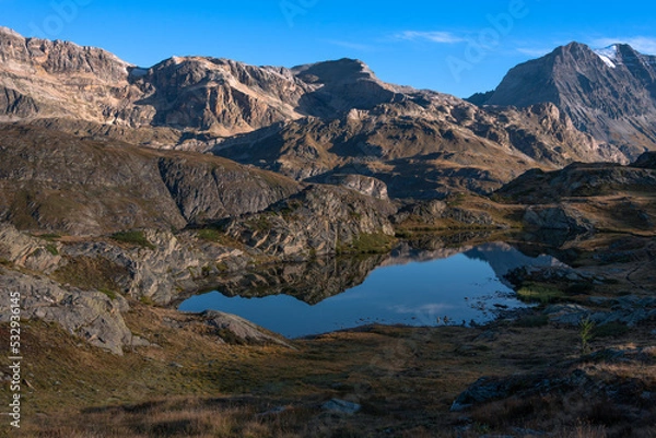 Fototapeta the beautiful lake of bellecombe surrounded by mountains in the french alps when the sun slowly rises in the sky
