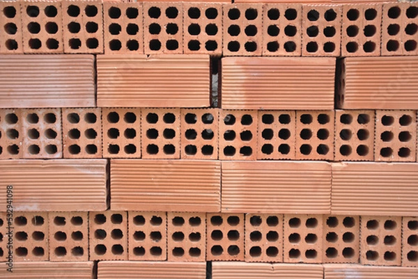 Fototapeta Background of baked clay bricks. Six-hole bricks stacked evenly. Construction materials.