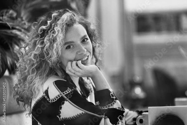 Fototapeta Pretty Young Woman With Curly Hair Relaxing In Cafe. Cute Girl Looking At Camera And Smiling