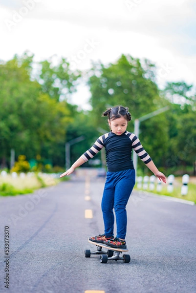 Obraz Child or kid girl playing surfskate or skateboard in skating rink or sports park at parking