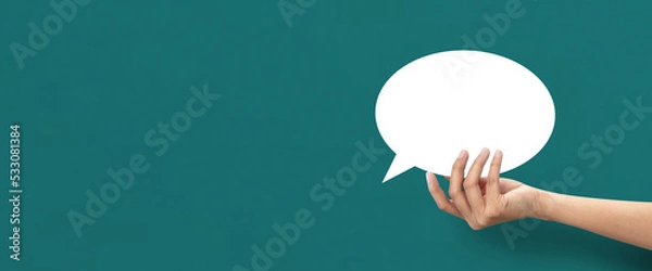 Fototapeta Hand holding shape of speech bubble icon on blue background.