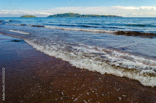 Fototapeta Sanda Island and Sheep Island with beach and waves at Southend near Mull of Kintyre Scotland