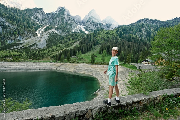 Obraz Boy stand against lake and mountains at Vorderer Gosausee, Gosau, Upper Austria.