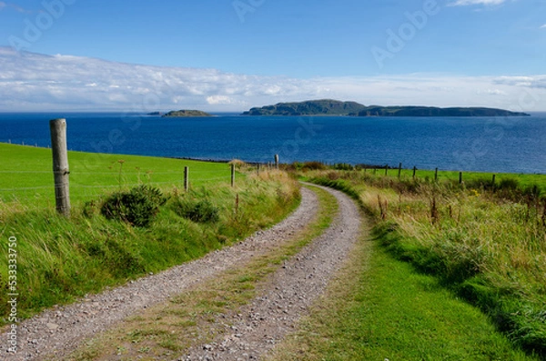 Fototapeta Country lane narrow track through farm fields to beach at Southend near Mull of Kintyre Scotland with view of  Sanda Island and Sheep Island