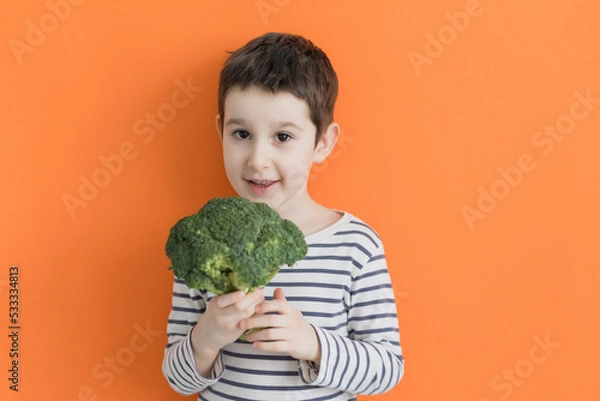 Obraz Child with vegetable broccoli orange background