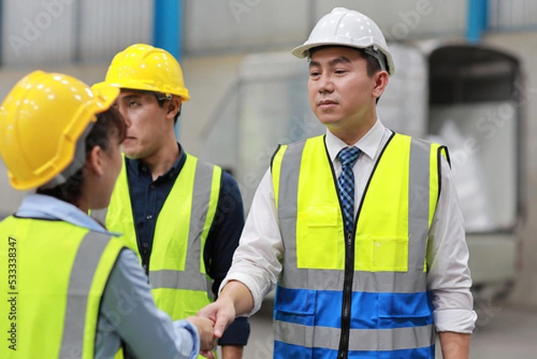 Fototapeta Group of technician engineer and businessman in protective uniform standing and discussing, researching, brainstorming and planning work together with protection mask at industry manufacturing factory