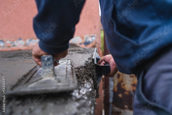Obraz A close up of worker hands putting a concrete on the ground and spreading it with tools