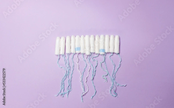 Fototapeta Many sanitary tampons lie in a row on a purple background. Menstrual cycle and pregnancy. Negative pregnancy test and contraceptives