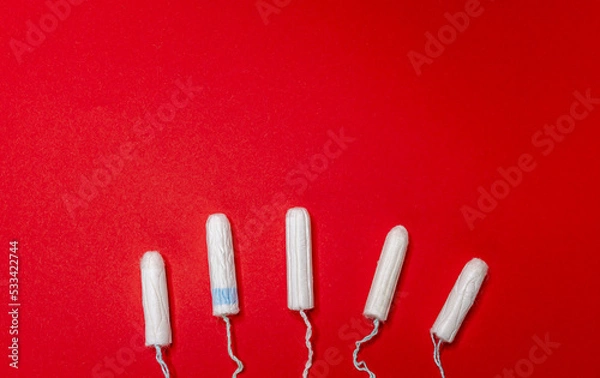 Fototapeta Many sanitary tampons lie on a red background. Menstrual cycle and pregnancy. Negative pregnancy test and contraceptives