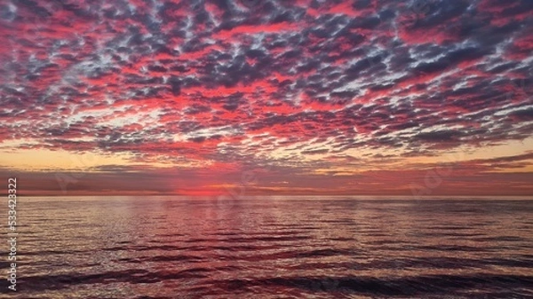 Obraz The first signs of sunrise against the background colored clouds and calm surface of the sea