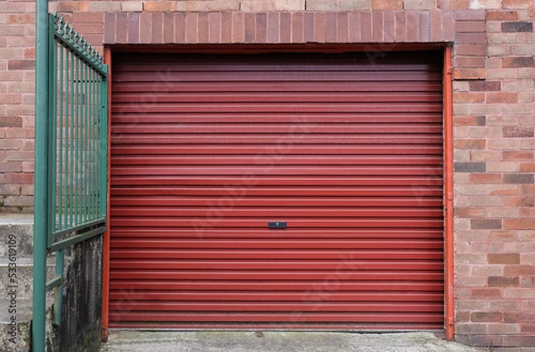 Obraz A red metal roll-up garage door at a house.