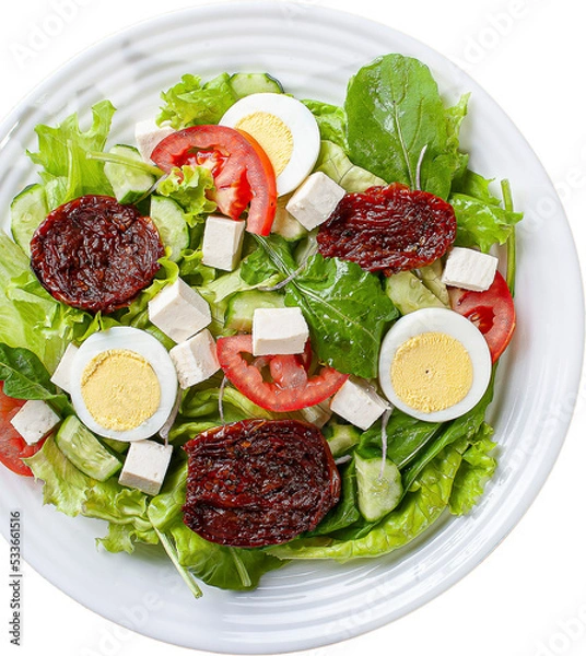 Fototapeta Green salad with lettuce, arugula, cucumber, cheese, sun-dried tomatoes and boiled egg.