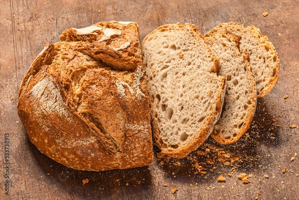 Fototapeta Sliced wholegrain bread on dark ructic wooden background closeup. Fresh bread Top view. .