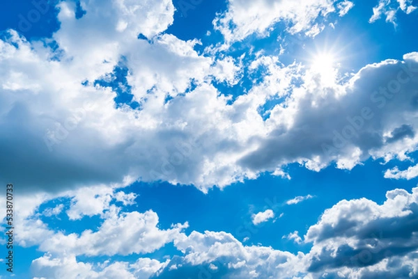 Fototapeta Thunderclouds on the blue sky. The sun peeks through the rain clouds. Sky before the rain