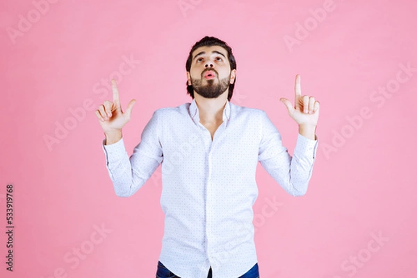 Obraz Person with blurred face wearing a white shirt making peace signs against a pink background