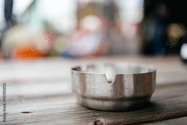 Obraz Metallic silver  shiny ashtray on a top of wooden table with blurred background