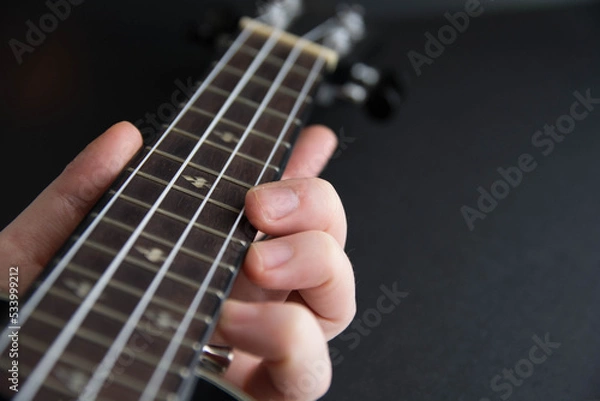 Fototapeta Close up ukulele isolated on dark background. Copy text.